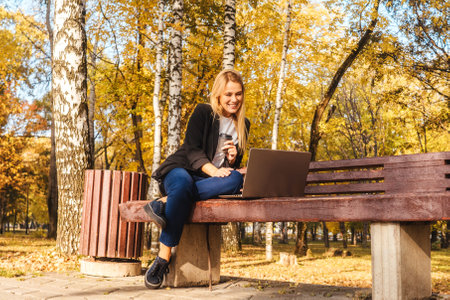 Young businesswoman working on bench in park.の写真素材