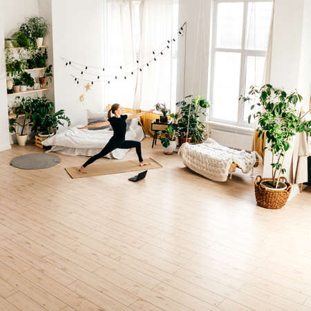 Young woman practicing yoga indoor, watch tutorial.の写真素材