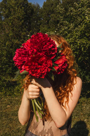 Young beautiful womanl holds peonies in hands.の写真素材