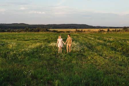 Walking loving couple in the field. Sunset.の写真素材