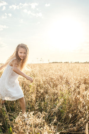 Little girl run in field, sunset light.の写真素材