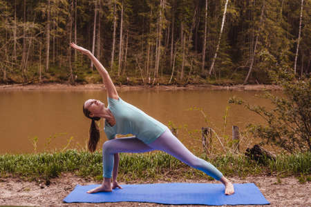 Young woman making yoga near river. Evening.の写真素材
