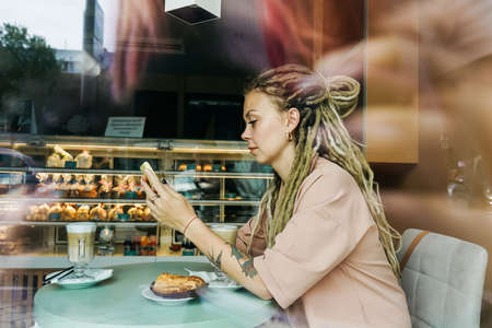 Caucasian woman with dreadlocks sitting in cafe.