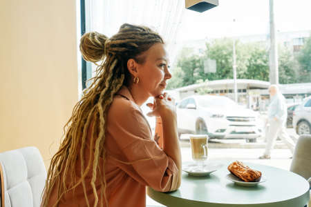 Caucasian woman with dreadlocks sitting in cafe.の写真素材
