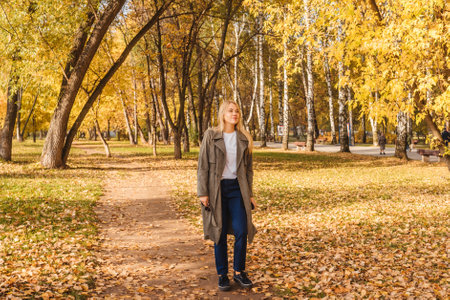 Woman in coat walking in autumn park.の写真素材