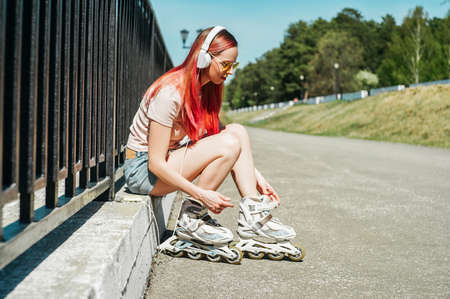 Woman fastens the rollers on road background.