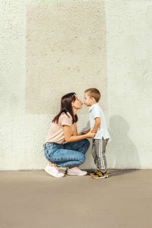 Mother and little son kiss near wall.の写真素材