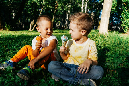 Kid boys eating ice cream on grass.の写真素材