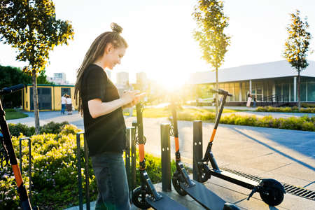 Woman rent an electric scooter in park.