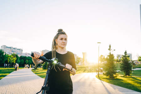 Woman rent an electric scooter in park.の写真素材