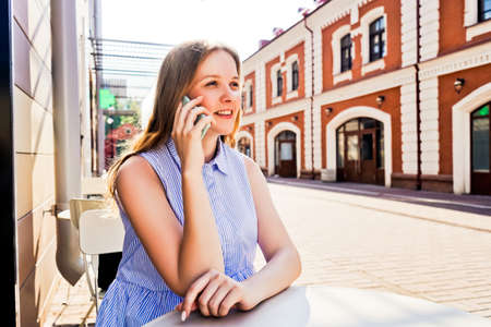 Smiling woman talking on mobile phone outdoors.の写真素材