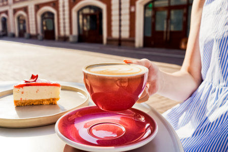 Cup of latte coffee with cheesecake outside.の写真素材
