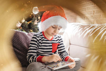 Boy play on tablet near christmas treeの写真素材