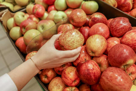 Female hands check red apples in supermarket.の写真素材