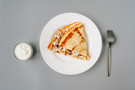 Person eating crepes with filling. Tasty breakfast on gray background. Fork and sauce.の写真素材
