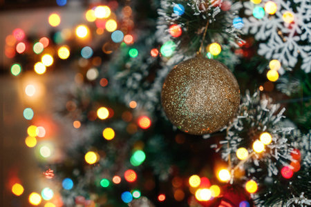 Golden christmas ball hanging on a branch. Decorations on the christmas tree. Multicolored bokeh.の写真素材