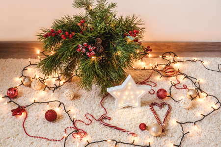 Front view of christmas decoration with garland on floor. Fir branches, balls and garland on carpet.の写真素材