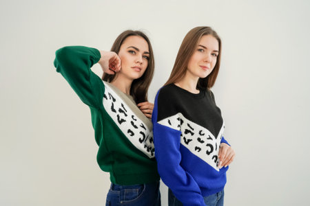 Two young women in sweaters on white background.の写真素材