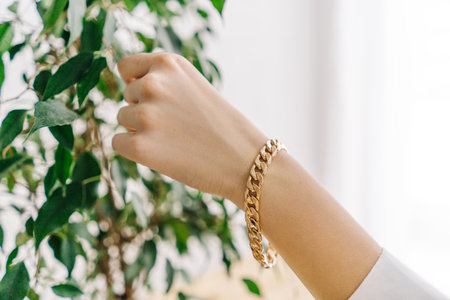 Golden bijouterie bracelet on woman hand. Plant.の写真素材