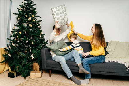 Happy family fight pillows on couch. Christmas.の写真素材