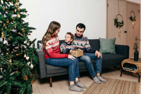 Happy family sitting on sofa near Christmas tree.の写真素材