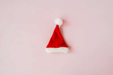 Red Christmas hat on pink background. Flat lay, copy space. Holiday minimal concept.の写真素材