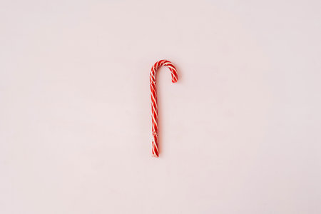 Red Christmas candy cane on pink background. Flat lay, copy space. Holiday minimal concept.の写真素材