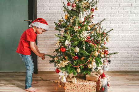 Happy child decorating the Christmas tree with balls. Christmas Eve concept.の写真素材