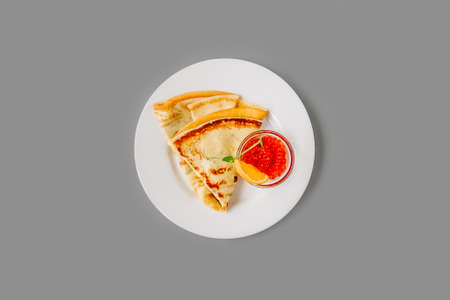 Person eating crepe with red caviar. Tasty breakfast on gray background, top view.の写真素材