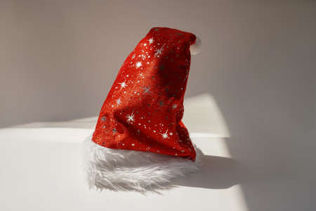 Red Santa Claus hat stand on white background. Christmas and New Year lifestyle concept. Sunny day.の写真素材