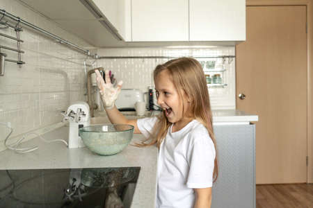 Girl cooking in kitchen. Little girl got her hand dirty in the dough.の写真素材