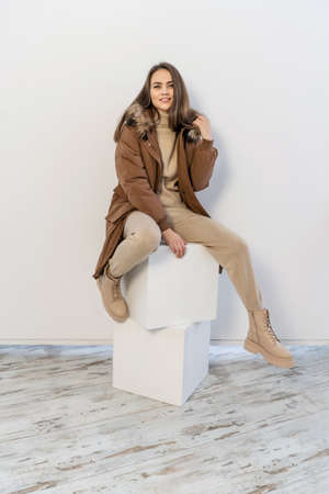 Young attractive woman wearing brown winter jacket on white background studio shot.の写真素材