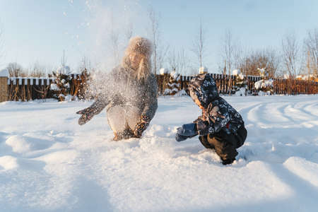 Happy mother and child throw snow and smiling. Winter walk and play.の写真素材