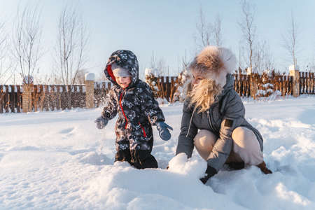 Happy mother and child throw snow and smiling. Winter walk and play.の写真素材