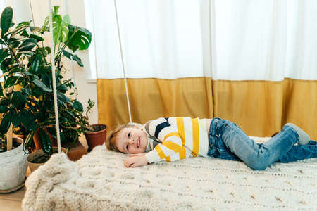 Happy little boy having fun and laughing on bed, front view.の写真素材
