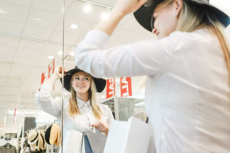 Woman tries on hat, looks in mirror.の写真素材