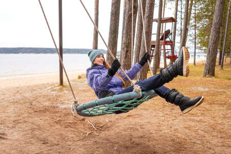 Beautiful woman on Swing, river background. Autumnの写真素材