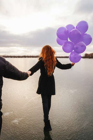 Love couple with violet balloons outdoor, back view.の写真素材