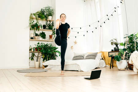 Young woman practicing yoga indoor, watch tutorial.の写真素材
