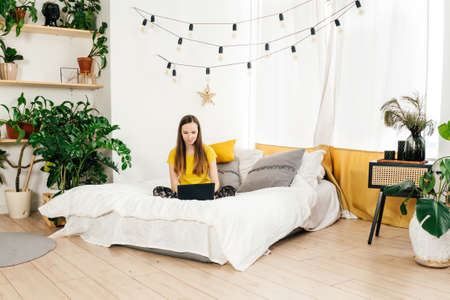 Smiling woman using laptop at home in bedroom.の写真素材