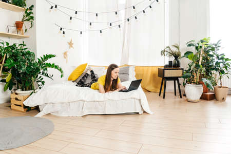 Smiling woman using laptop at home in bedroom.の写真素材