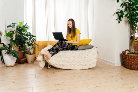 Smiling woman using laptop at home in bedroom.の写真素材