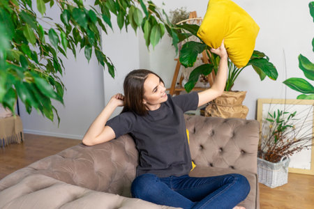 Young smiling woman in couch between plants.の写真素材