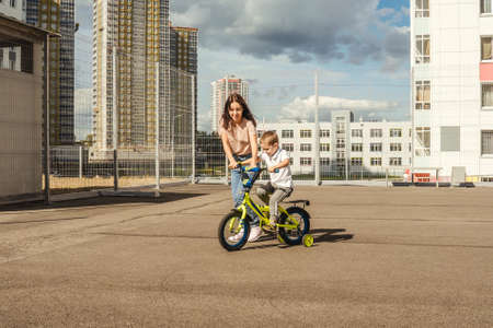 Boy rides a bike with his mother.の写真素材