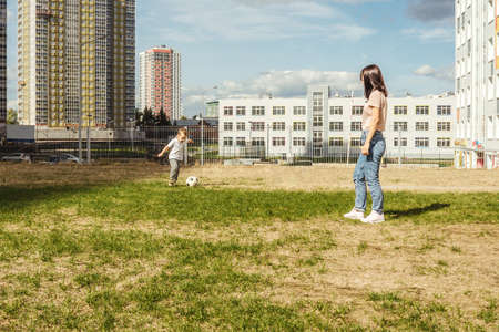 Mother play football with son on grass.の写真素材