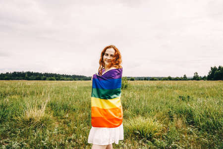 Lesbian woman with rainbow flag on field background. LGBTQ concept.の写真素材