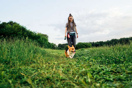 Woman with dreadlocks walk with dog corgi.の写真素材