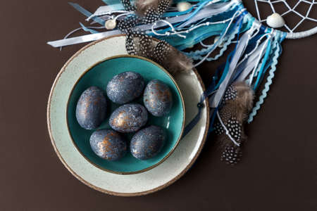 Easter concept of coloring eggs in hibiscus, eco dyes. Top view, Feathers as decoration.
