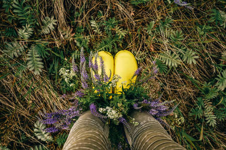 Yellow rubber boots with bouquet wildflowers. Top view.の写真素材