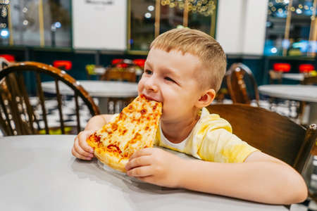 Child eats pizza in cafe, close up.の写真素材